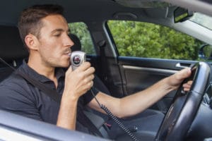 Man in car blowing into ignition interlock device